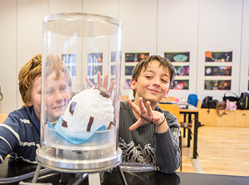 Experimenting in DESY's vacuum lab. Two boys look at an experiment. (Credit: DESY) src=